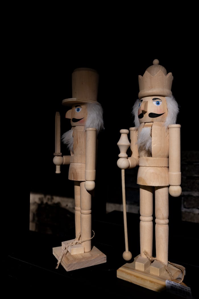 Two wooden nutcracker figures in a dark, dramatic lighting setting.